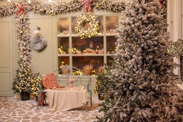 A casa coberta de neve é decorada para o ano novo. Pátio de inverno vintage, decorado com árvores de Natal, lanternas e um banco aconchegante e vitrine com bolos frescos. Foco seletivo suave.