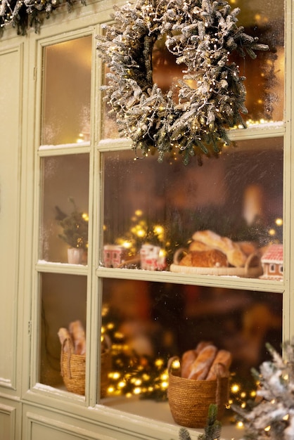 A casa coberta de neve está decorada para o ano novo Pátio de inverno vintage decorado com lanternas de árvores de Natal e uma vitrine com produtos assados frescos Foco seletivo suave