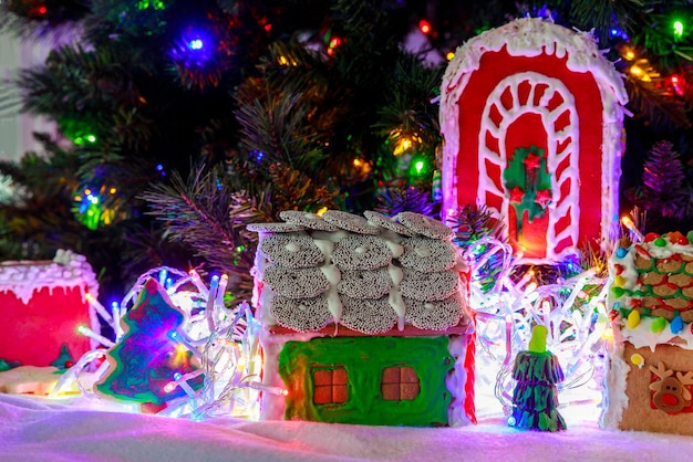 A casa de pão de gengibre é enquadrada por luzes de Natal desfocadas na árvore