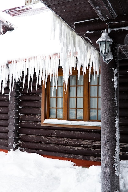 A casa de toras com o telhado gelado e pingentes de gelo