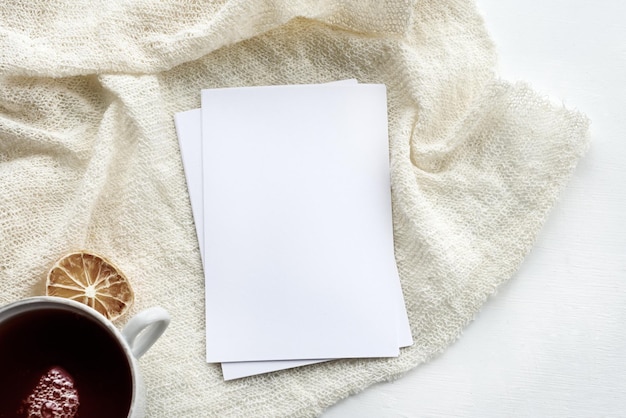 A cena do layout de papelaria em uma tecla leve um cartão vertical vazio e uma xícara branca de chá