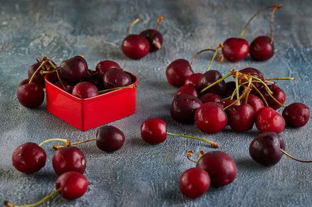 A cereja fresca ou a cereja doce com água deixam cair com um coração vermelho. Conceito para dia dos namorados