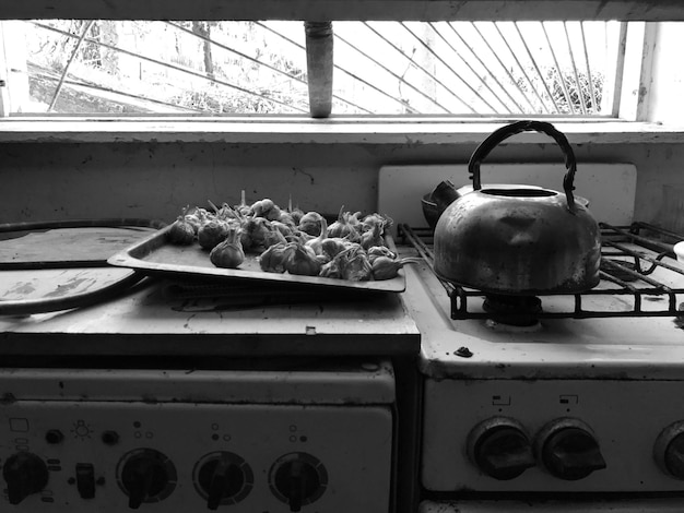 Foto a chaleira no fogão com alho no balcão da cozinha