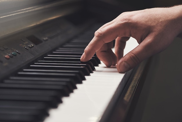 A chave para a música Tiro recortado da mão de um homem em um teclado de piano