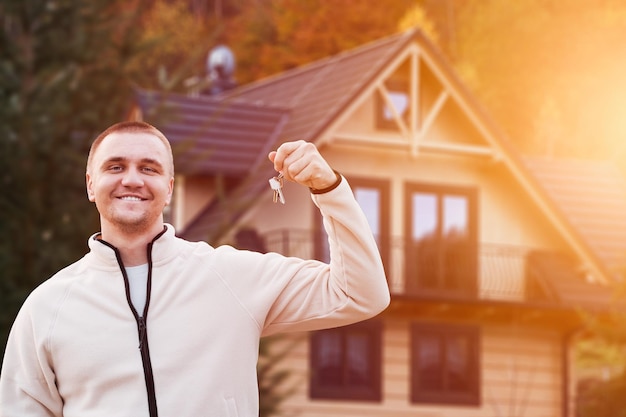 A Chave para a Propriedade da Casa Homem Feliz com Chaves na Frente de uma Casa Moderna Jovem cliente está tomando um empréstimo hipotecário para comprar uma casa Investindo no Sonho