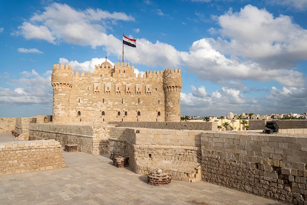 A cidadela de qaitbay ou o forte de qaitbay é uma fortaleza defensiva do século xv localizada na costa do mar mediterrâneo pessoas comuns caminham nas proximidades