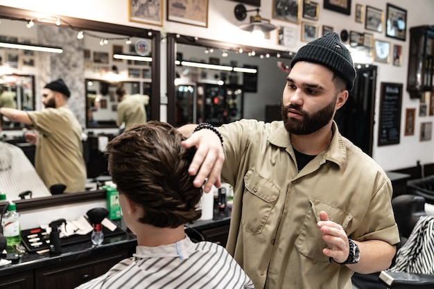 A cliente recebe corte e modelagem de cabelo em salão de beleza. Barber atende o cliente.