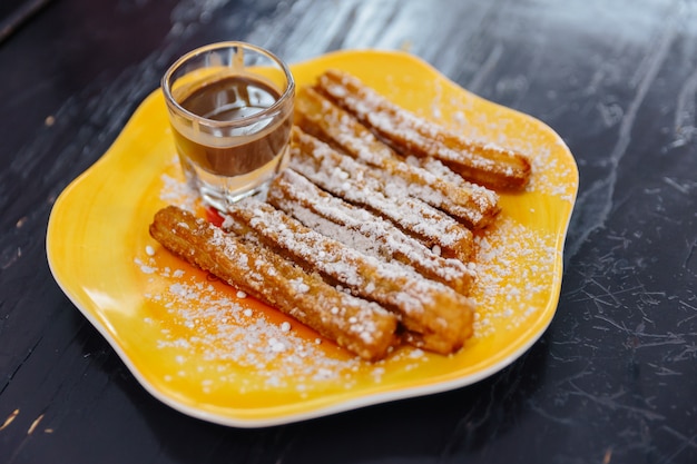 A cobertura de Churros com açúcar de crosta de gelo serviu com molho do nutella na placa amarela.