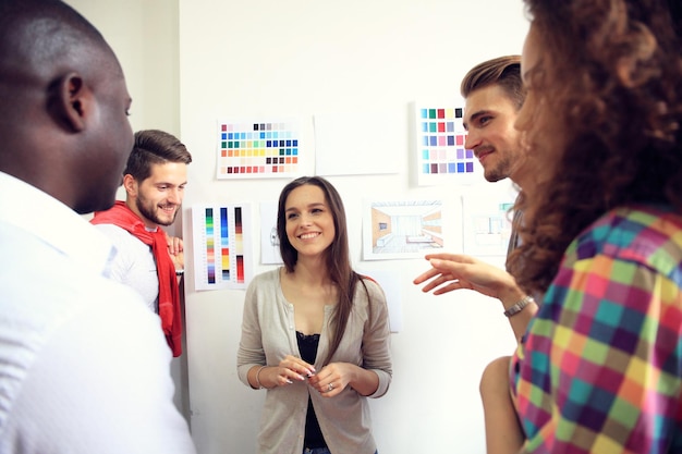 A colaboração é a chave para os melhores resultados Grupo de jovens modernos em roupas casuais inteligentes planejando a estratégia de negócios enquanto uma jovem aponta para o infográfico exibido na parede branca do escritório