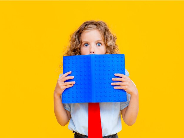 A colegial assustada cobriu o rosto com um livro azul. colegial com livro perto do rosto