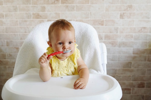 A colher infantil feliz do bebê come-se em casa