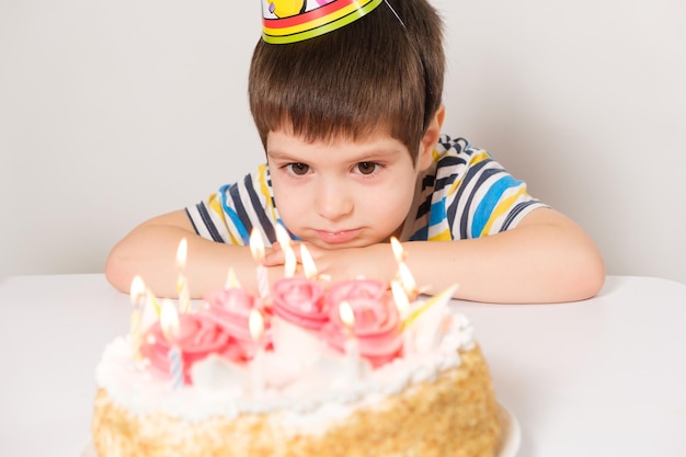 A comemora um aniversário senta-se na frente de um bolo com velas