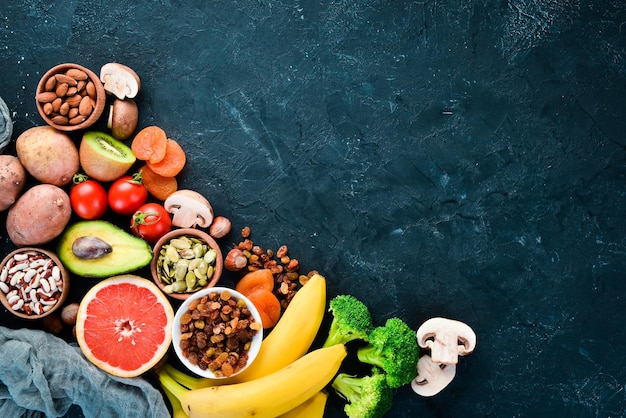 A comida contém potássio natural k batatas cogumelos banana tomate nozes feijão brócolis abacate vista superior sobre um fundo preto