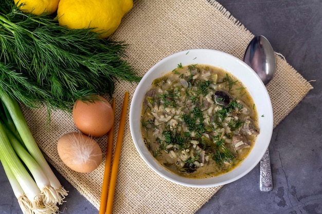 A composição de páscoa Sopa grega nacional Magiritsa em uma tigela que é preparada uma vez por ano na Páscoa em uma mesa de madeira fechada