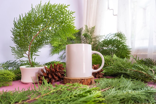 A composição exibe o produto. caneca branca na velha madeira redonda com decoração de folhas de abeto. ideias de exibição de produtos de verão