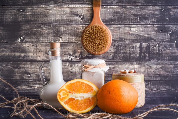 A composição leiga com produtos para o corpo. um pote de creme natural, uma garrafa de óleo de coco e uma laranja madura