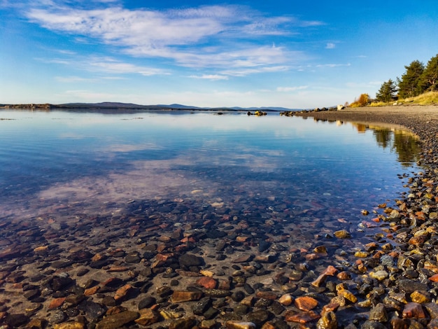 A costa do Mar Branco em um dia ensolarado com pedras na água Karelia