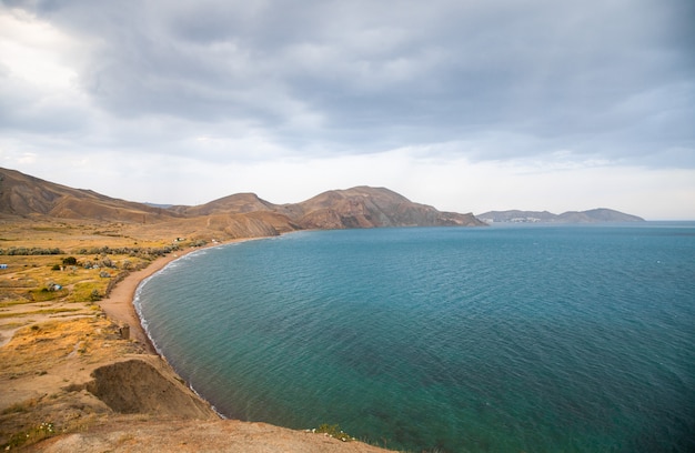 A costa do mar negro na crimeia, em koktebel no camaleão do cabo ao pôr do sol