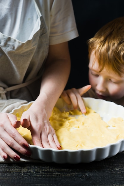 A criança ajuda a mãe a cozinhar um bolo, cozinhar.