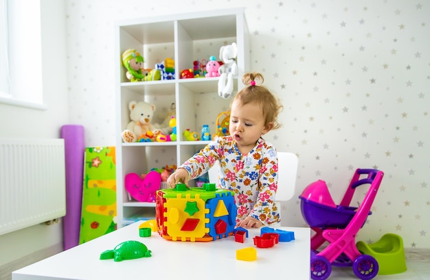 A criança brinca com brinquedos na sala. Foco seletivo.