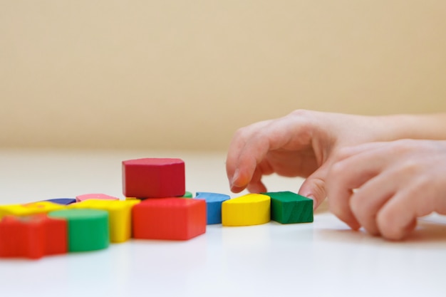 A criança brinca com figuras coloridas. Detalhes do brinquedo nas mãos.