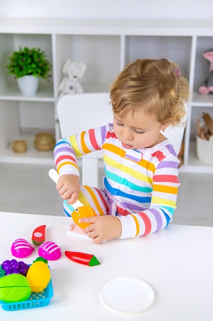 A criança brinca de brinquedos de cozinha e comida Foco seletivo