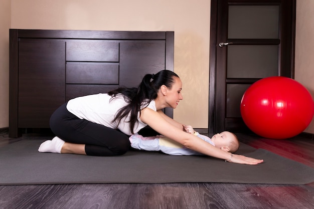 A criança brinca, faz exercícios, faz ginástica com a mãe em casa.