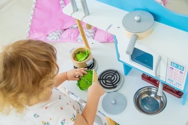 A criança brinca na cozinha e cozinha foco seletivo