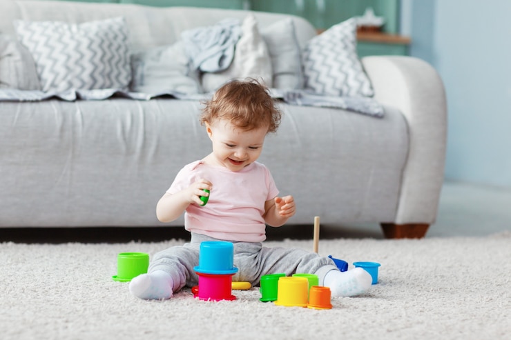 A criança brinca no chão em um tapete leve com brinquedos brilhantes, constrói uma torre