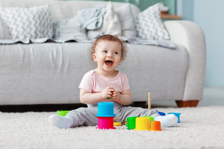 A criança brinca no chão em um tapete leve com brinquedos brilhantes, constrói uma torre