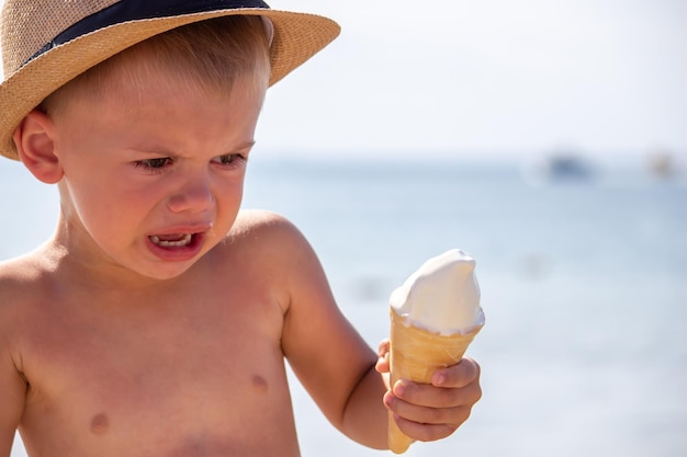 A criança chora e come sorvete na praia