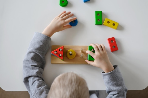 A criança coleta um brinquedo de madeira coloridoClassificador lógico multicoloridoVista superior