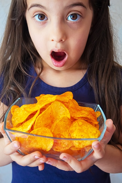 Foto a criança come batatas fritas. foco seletivo