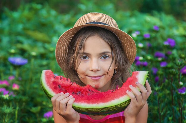 A criança come melancia no verão. Foco seletivo.