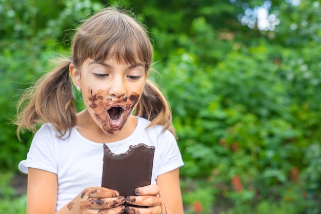 A criança come uma barra de chocolate.