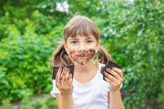 A criança come uma barra de chocolate.