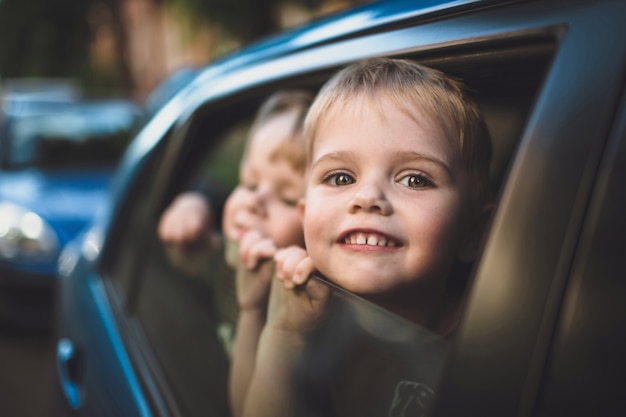 Foto a criança de sorriso olha fora de uma janela do carro