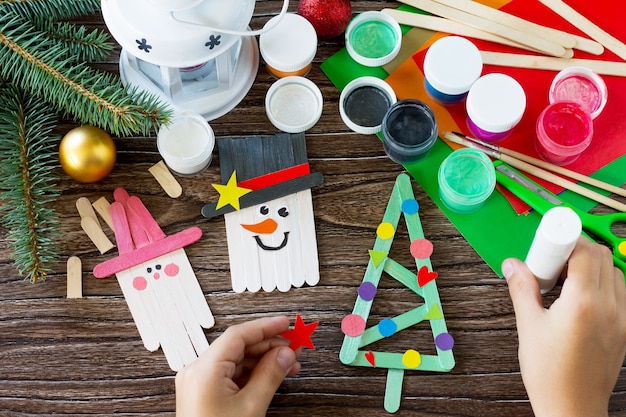 A criança desenha detalhes de decoração de Natal ou presente de Natal Boneco de neve feito à mão