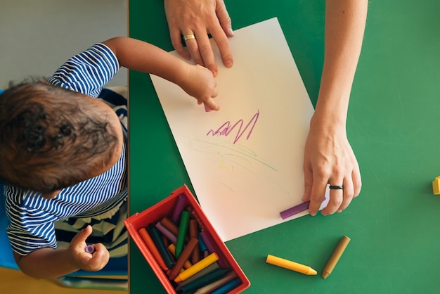 Foto a criança e a mãe estão desenhando em um papel. conceito de jardim de infância.
