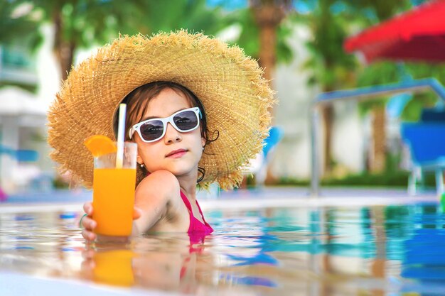 A criança está bebendo um coquetel na piscina