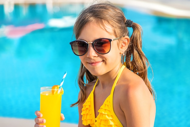 A criança está bebendo um coquetel na piscina