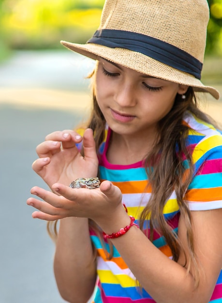 A criança está brincando com o sapo Foco seletivo