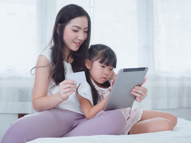 A criança está brincando na cama com a mãe dela