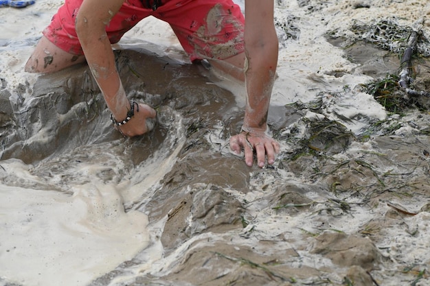 A criança está brincando na praia, jogo com areia e mãos, detalhe das mãos