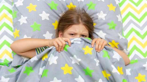 Foto a criança está deitada na cama e não quer se levantar para ir à escola.