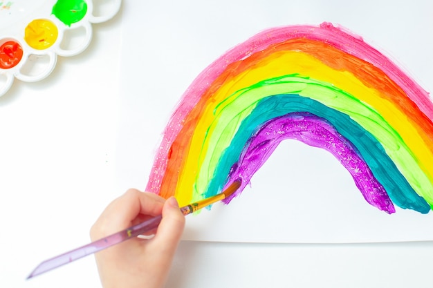 A criança está desenhando o arco-íris.