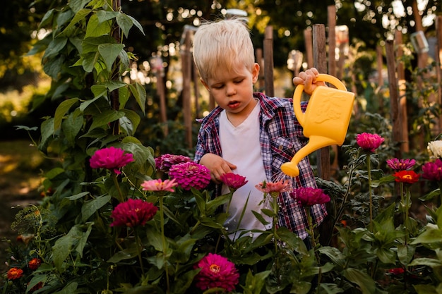 A criança está regando flores no jardim usando um regador