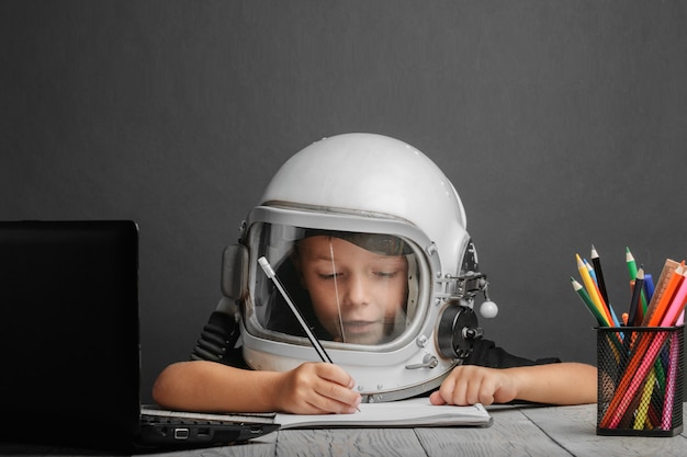 A criança estuda remotamente na escola, usando um capacete de astronauta. de volta à escola