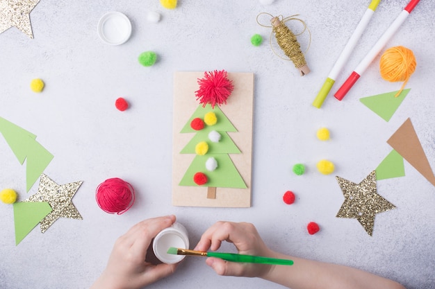 A criança faz um cartão de felicitações colagem de papel de natal, projeto de arte infantil, para crianças foto de alta qualidade