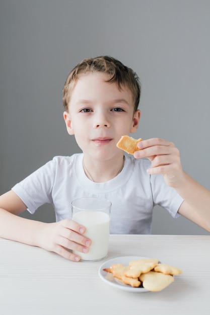 A criança fica feliz em comer biscoitos caseiros com leite